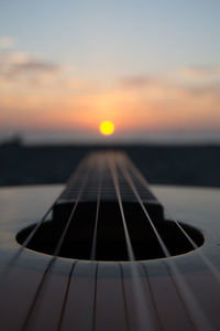 Close-up of guitar against sky during sunset