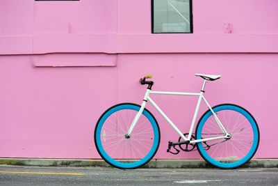 Bicycle parked against pink wall