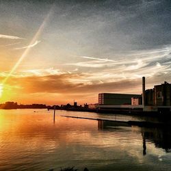 Sunset over river with buildings in background