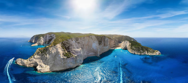 Panoramic view of sea by mountain against sky