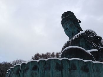 Low angle view of statue against sky during winter