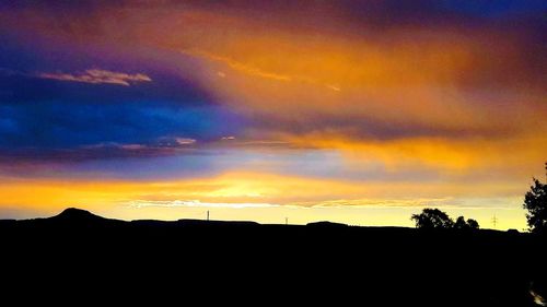 Silhouette landscape against dramatic sky during sunset