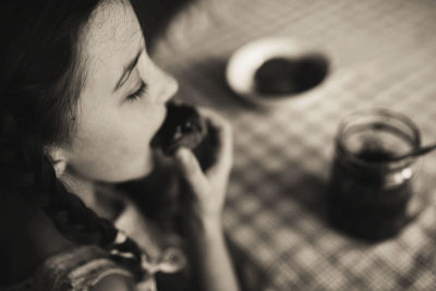 Cute funny toddler girl eats sweet bun  breakfast. happy child eating bread roll with strawberry jam