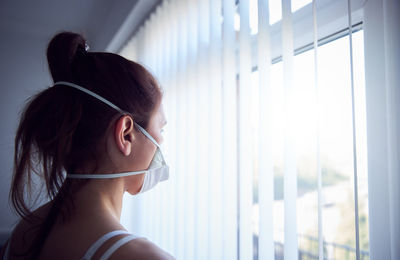 Portrait of young woman looking through window