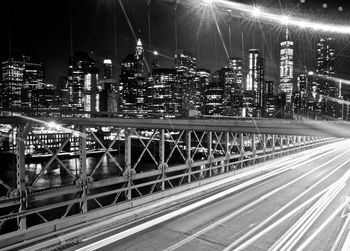 Light trails on road by illuminated buildings in city at night