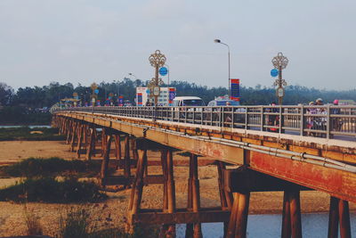 Vehicles on bridge over river against sky