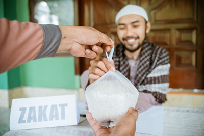 Hands of man helping with rice bag at mosque