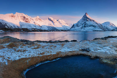 Scenic view of frozen lake by snowcapped mountains against sky