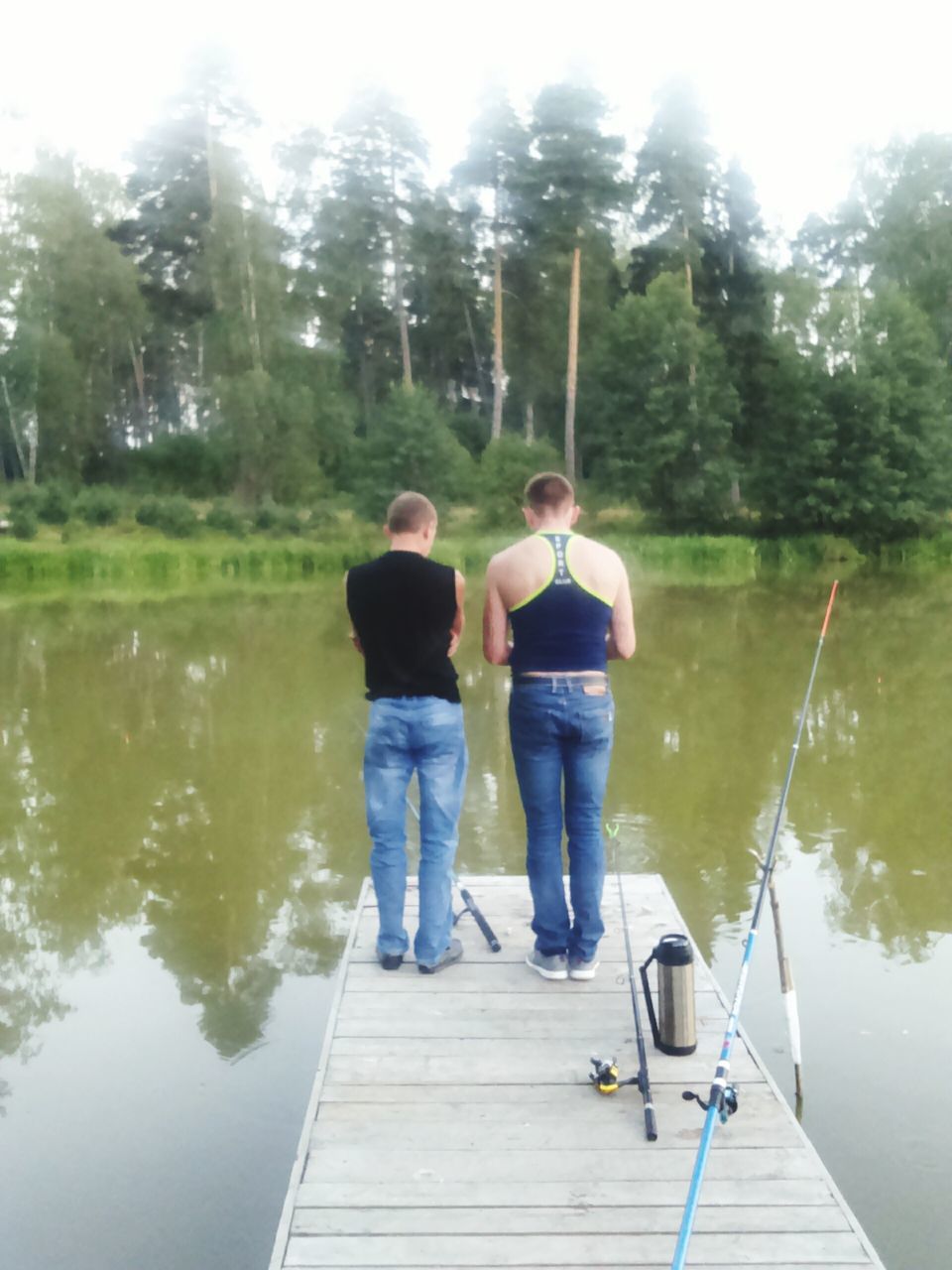 REAR VIEW OF PEOPLE ON WOODEN PIER OVER LAKE