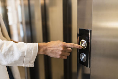 Hand of businesswoman pushing elevator button