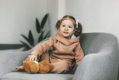 Portrait of smiling boy sitting on sofa at home