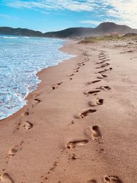 Footprints on sand at beach against sky