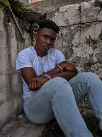 Full length of teenage boy sitting against wall