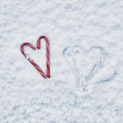 High angle view of heart shape made with candy canes on snow