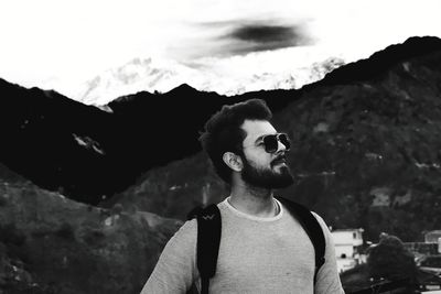 Portrait of young man looking away against mountains