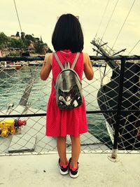 Rear view of girl standing on footbridge over lake