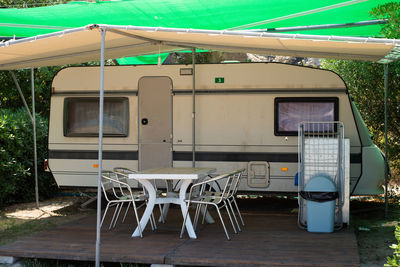 Stationed caravan at seaside camp with tent, chairs and table.