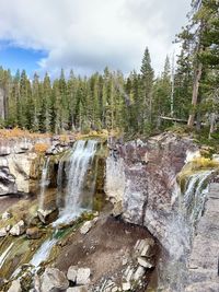 Scenic view of waterfall in forest against sky