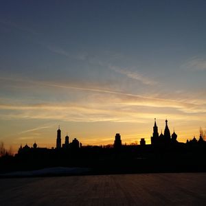 Silhouette of buildings against cloudy sky during sunset