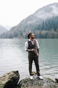 Full length of man standing on rock by lake