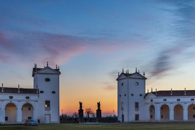 Tower amidst buildings against sky during sunset