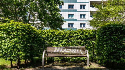 Empty bench in park against building