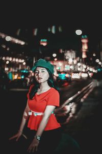 Portrait of young woman standing in city at night