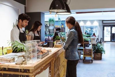 Customer paying saleswoman at checkout counter in store