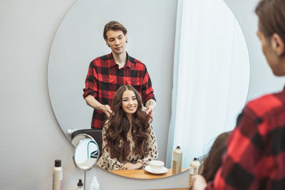 Stylist barber styling long hair for beautiful asian young woman in the beauty salon, working moment