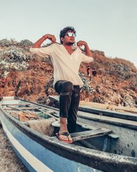 Full length portrait of young man standing against sky