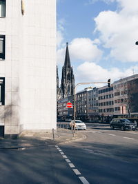 Road by buildings against sky in city