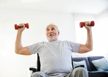 Low angle view of man lifting dumbbells at home