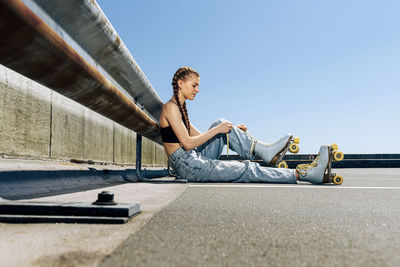Girl tying up her roller skates, urban background