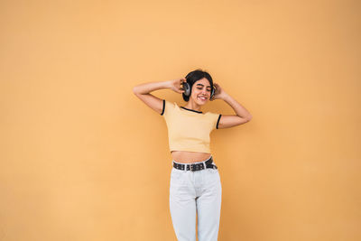 Portrait of smiling young woman standing against wall