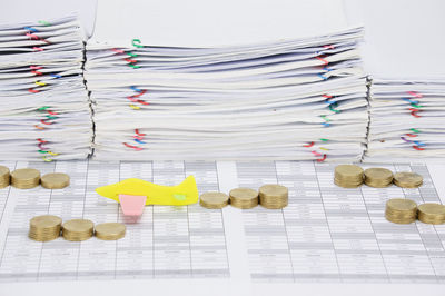 High angle view of stacked coins with airplane model on financial documents