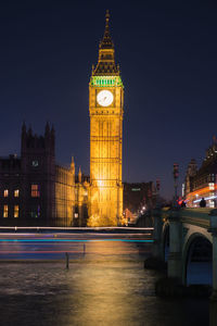 Low angle view of big ben by bridge over river against sky