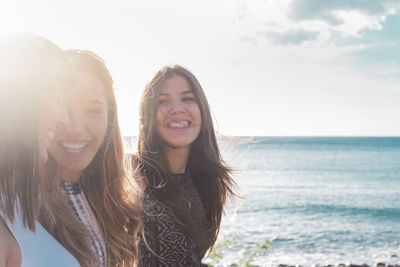 Happy friends at beach against sky