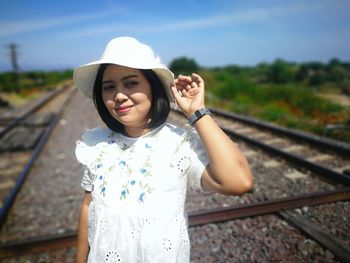 Portrait of smiling young woman standing on railroad track