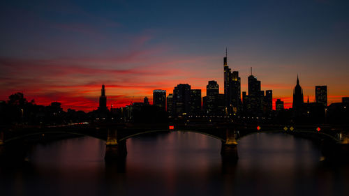 Scenic view of river amidst buildings against sky during sunset