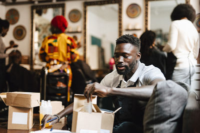 Male hair expert packing beauty product in box at barber shop