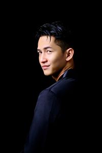 Portrait of young man looking away against black background