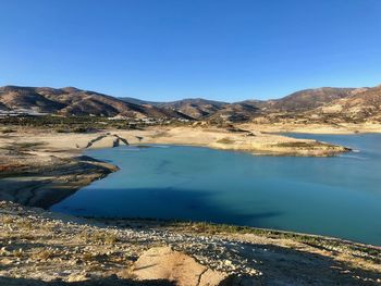 Scenic view of lake and mountains against clear blue sky