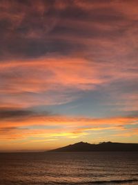 Scenic view of sea against dramatic sky during sunset