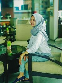 Young woman sitting on table in restaurant