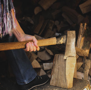 Low section of man cutting wood with axe