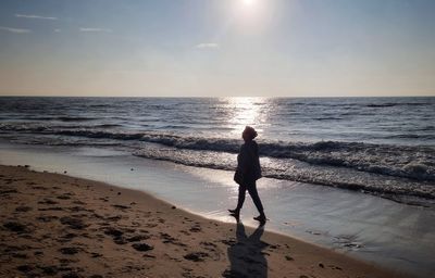 Full length of man standing on beach against sky during sunset