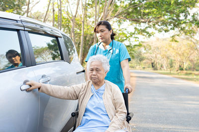 Doctor assisting senior woman on wheelchair outdoors