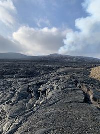 Smoke emitting from volcanic landscape against sky