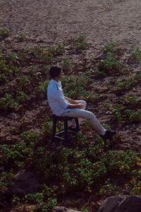 Side view of young man sitting on land