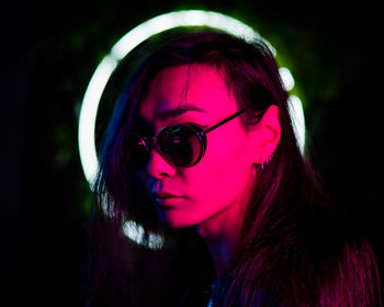 Close-up of young man wearing sunglasses against black background